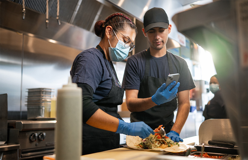 Une employée apprend à rouler un burrito façon Sisig.
