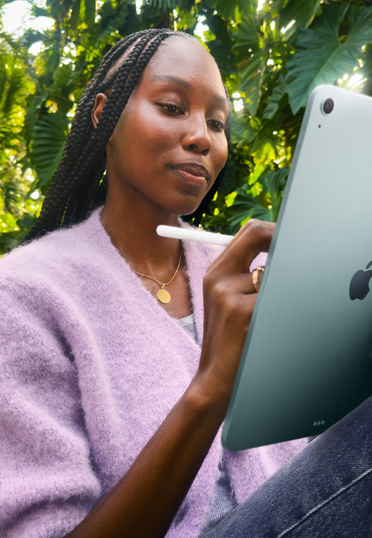 一名學生坐在户外，她手拿著一台 iPad 和一支 Apple Pencil Pro。