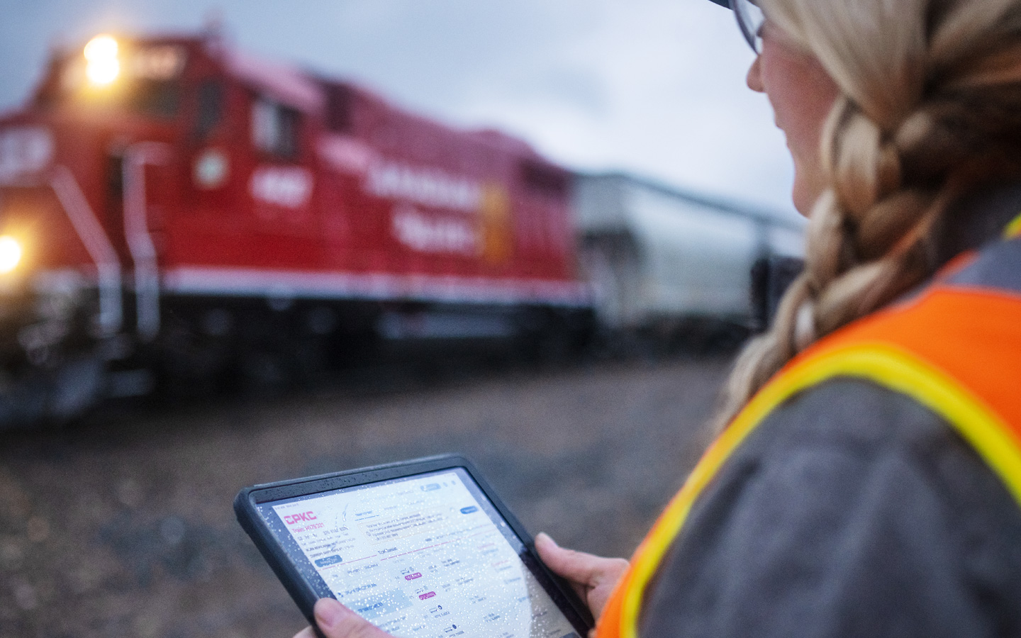 Eine Bahnmitarbeiterin an einem Bahnhof bewertet Zugfahrpläne auf dem iPad