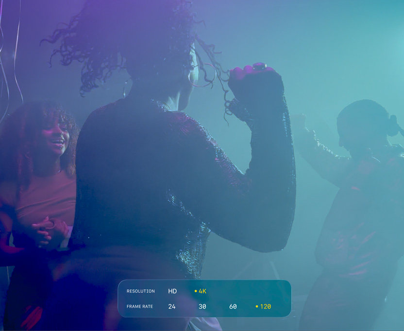 En skjerm med tre personer som danser i svak belysning, viser kapasiteten til 4K Dolby Vision i 120 bps.
